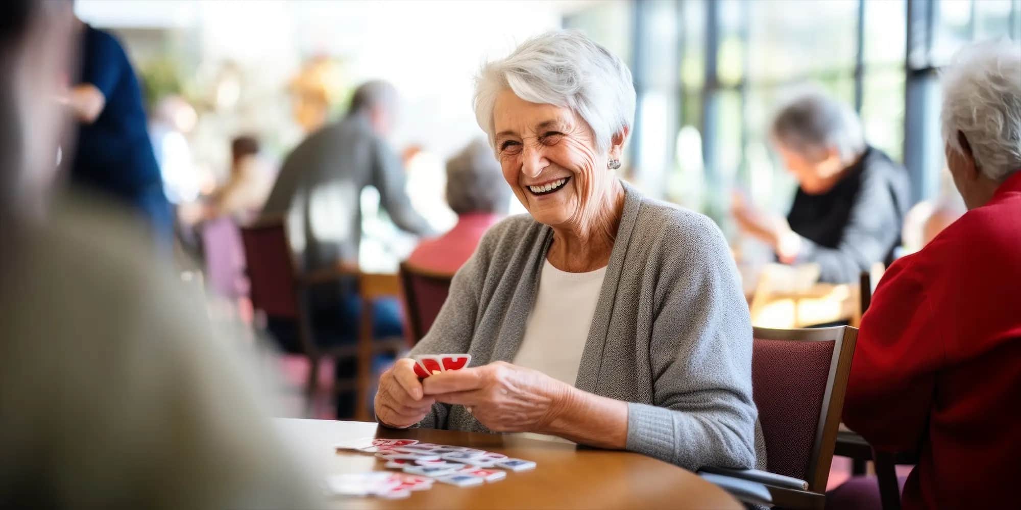 A senior women smiling as she plays a game at a table in memory care.